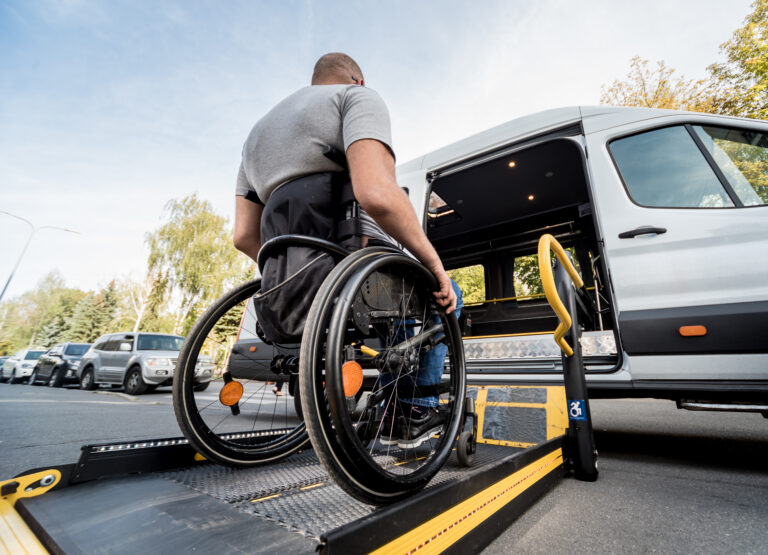 A man in a wheelchair moves to the lift of a specialized vehicle for people with disabilities